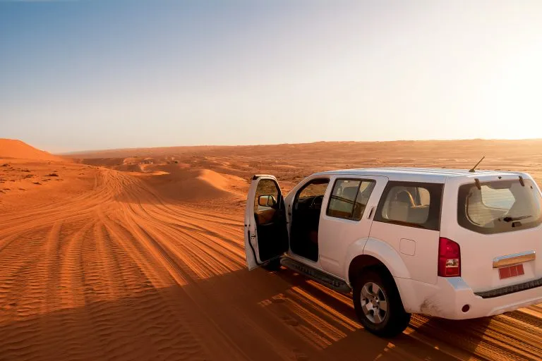 Off-road vehicle in the wahiba sands desert dunes at sunset (Oman)